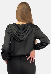 Czarna satynowa hoodie o miękkiej fakturze, z przednią kieszenią i sznurkiem. Slim fit z długimi rękawami i zaokrąglonym dołem.