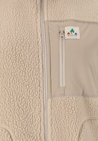 Beige fleecejacka med mjukt texturerat tyg, vertikal dragkedja och dragkedjeförsedd bröstficka med en Whistler-logotyp.