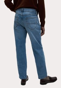 Vaqueros de mezclilla azul claro con corte recto, que presentan dos bolsillos traseros y una cinturilla sin costuras, combinados con mocasines marrones.