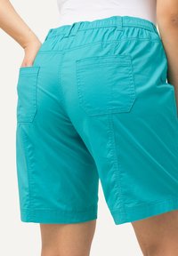 Pantalones cortos turquesa con una cinturilla elástica, dos bolsillos traseros de parche y una tela ligera y suave. Presentan un dobladillo recto y costuras planas.