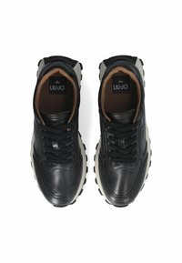 Sneakers in pelle nera con suola bianca chunky, dotate di lacci neri, foderato in marrone e con logo sulla linguetta. Texture liscia e forma arrotondata.