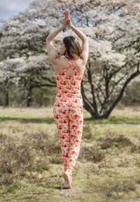Mönstrad träningsklädset i orange, röd och rosa nyanser, med en ärmlös topp med nyckelhålsdetalj och kroppsnära leggings.