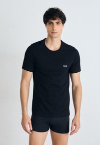 Schwarzes Baumwoll-T-Shirt mit Rundhalsausschnitt, kurzen Ärmeln und kleinem weißen 'BOSS'-Logo auf der Brust. Glatte Textur, normale Passform.