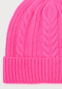 Heldere roze gebreide beanie met omgevouwen geribbeld rand en twee verticale kabels op een lichte achtergrond.