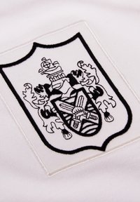 Witte stof met een zwart geborduurd schildembleem. Het schild vertoont ingewikkelde ontwerpen en motieven, waaronder leeuwen en zwaarden.