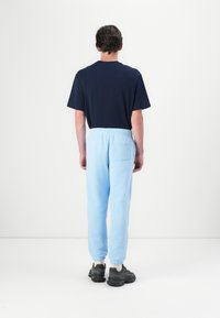 Marineblå bomull T-skjorte kombinert med lyseblå joggebukser med elastisk midje og baklomme, komplementert med mørke sneakers.