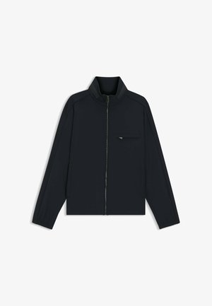 Veste noire légère avec une fermeture éclair à l'avant, un col montant, des manches longues et une petite poche zippée sur la poitrine gauche.