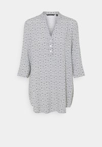 Czarna i biała tunika w wzory z dekoltem w kształcie litery V, trzema guzikami i rękawami o długości trzech czwartych, wyeksponowana na jednolitym białym tle.