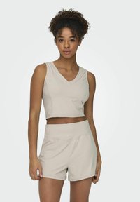 Jasnoszary sportowy crop top z dekoltem w serek i prążkowaną teksturą, zestawiony z dopasowanymi szortami o wysokim stanie z gładką talią i kieszenią.