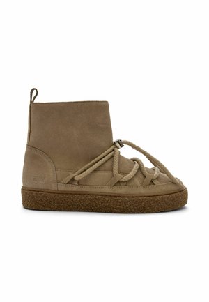 Bottine beige en daim avec une semelle épaisse marron et un laçage unique en corde épaisse sur le devant et autour de la cheville.