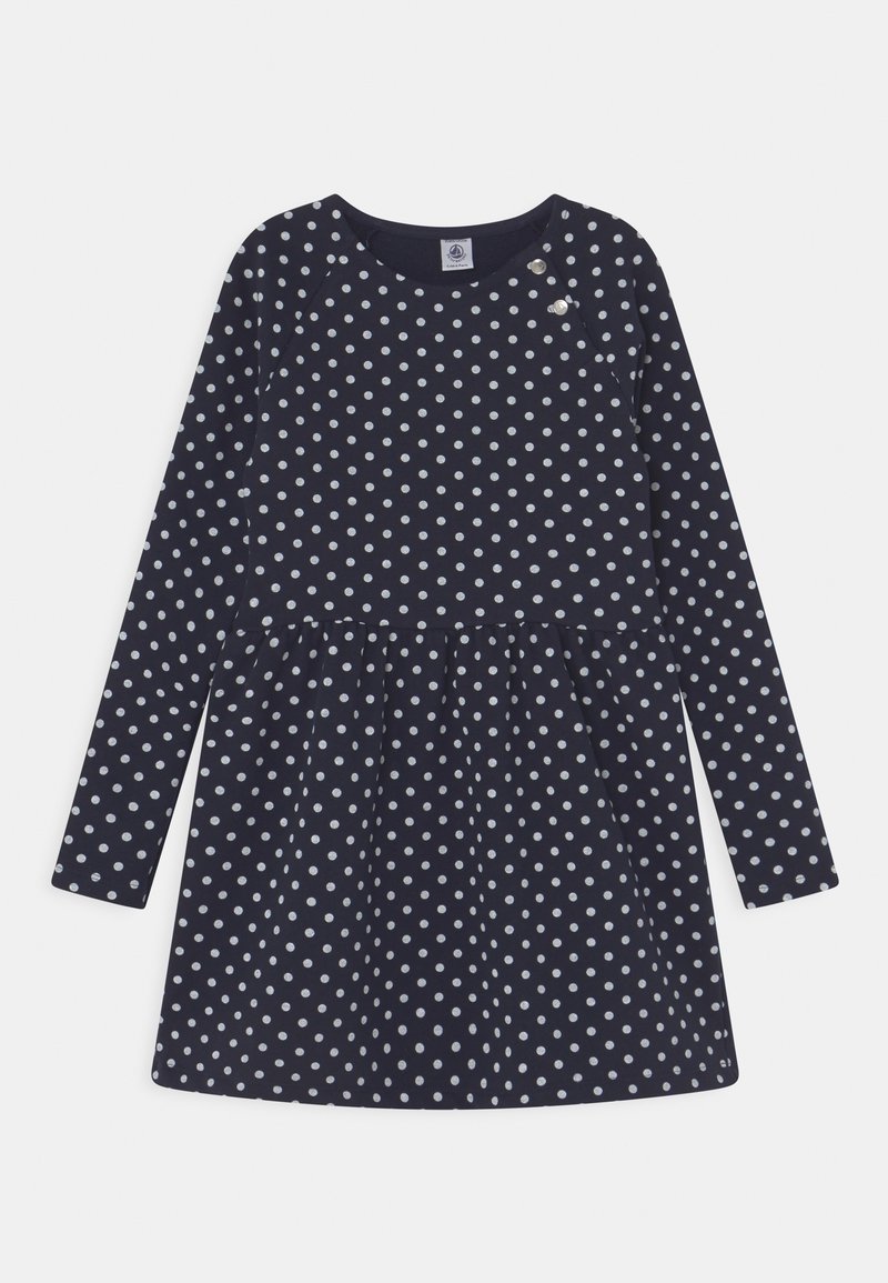 Marint blå långärmad klänning med vita prickar, med en rynkad midja och tryckknappar på axlarna, tillverkad av mjukt material.