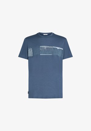 Sininen lyhythihainen T-paita, jossa on vaakasuora nauha abstrakteja, teksturoituja kuvioita rinnan kohdalla ja pyöreä kaula-aukko.