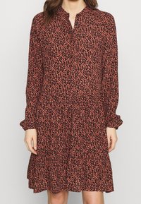 Dlouhý rukáv, šatové šaty po kolena v měděné barvě s černým květinovým potiskem, s knoflíkovou légou a nabíranou skládanou sukní. Jemná, lehká látka.