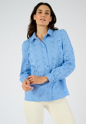 Hellblaues Hemd mit langen Ärmeln und Knopfleiste, das mit Ausschneidemustern versehen ist und aus strukturiertem Stoff besteht. Weiches, atmungsaktives Material mit einer figurbetonten Passform.