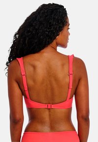 Koraal kleurige bikini-top met verstelbare bandjes, met een gladde textuur en een haaksluiting op de rug. Eenvoudig ontwerp, zonder patronen of accenten.