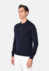 Polo a maniche lunghe di colore blu navy in maglia con colletto, patta con tre bottoni e polsini a coste. Tessuto morbido e design fitted.