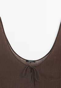 Haut marron sans manches avec un décolleté plongeant et une fermeture à nouer à l'avant en tissu léger.