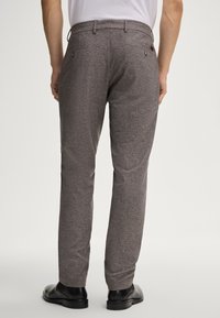 Grau strukturierte Hosen mit geradem Schnitt, ausgestattet mit zwei Gesäßtaschen und einem Bund. Kombiniert mit schwarzen Schuhen für einen abgerundeten Look.