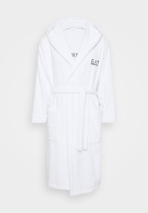 Λευκή ρόμπα ντους φτιαγμένη από μαλακό πετσέτα. Διαθέτει κουκούλα, μακριά μανίκια, ζώνη και δύο μπροστινές τσέπες. Περιλαμβάνει κεντημένο λογότυπο.