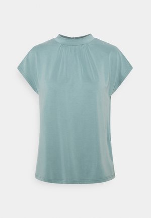 Lichtblauwe blouse met korte mouwen, een hoge halslijn en een zachte geplooide stofdetail aan de voorkant.