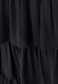 Black crinkled fabric with tiered layers creating soft, vertical folds and a flowing texture.
