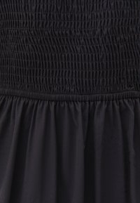 Schwarzes Kleid mit gerafftem Oberteil, das von Falten geprägt ist, fließender Stoffstruktur und einem ausgestellten Saum am unteren Ende.