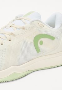 Weißer Mesh-Sportschuh mit grünen Akzenten und einem geschwungenen Logo, ausgestattet mit einer strukturierten Sohle und leichten Schnürsenkeln für einen sicheren Sitz.