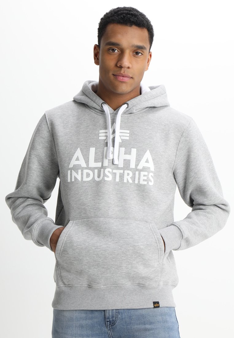 Sudadera gris con estampado blanco de "ALPHA INDUSTRIES", capucha con cordón, bolsillo canguro, puños y dobladillo acanalados. Textura de tela suave.