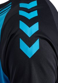 Svart idrottströja med blå chevronmönster på axeln och ett diagonalt blått rand. Tillverkad av ett mjukt, flexibelt tyg.