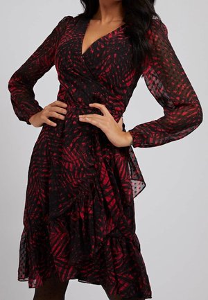 Robe portefeuille à motifs noirs et rouges avec de longues manches transparentes, décolleté en V, et volants superposés à l'ourlet. Texturée avec des pois.