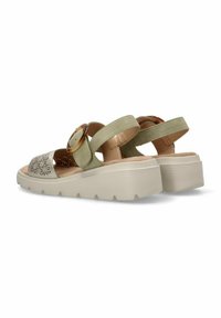 Sandalias de dos bandas en verde y beige con un acento circular y perforaciones florales en la correa de los dedos. Suela de goma elevada y texturizada.