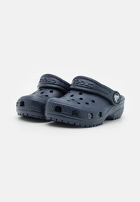 Navy blue Crocs clogs made of lightweight material with ventilation holes, back strap, textured sole, and raised logo detail on the side.