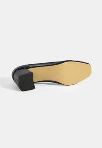 Schwarzer High-Heel-Schuh mit quadratischer Zehenpartie und dickem, strukturiertem schwarzen Absatz. Gelbe Sohle mit dezentem Grip-Muster, elegante glatte Oberfläche im oberen Bereich.