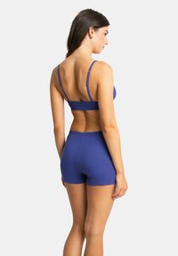 Ensemble de bralette et short côtelé bleu, avec des bretelles fines et une coupe ajustée, mettant en valeur une texture lisse et une construction simple.