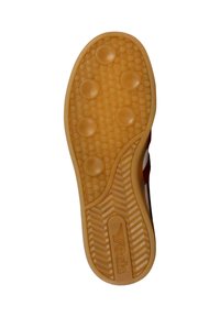 Suela de un zapato de color goma con agarres circulares, área del talón texturizada y la palabra "Avia" grabada cerca del talón.