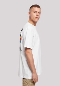 White cotton t-shirt with short sleeves, featuring colorful graphic designs and text on the back, straight-cut hem, and relaxed fit.