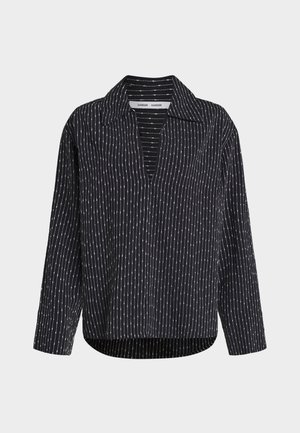 Blusa negra de manga larga con rayas verticales blancas de puntos, cuello abierto y ajuste relajado.