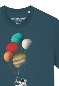 Teal T-shirt met een grafische afbeelding van een astronaut die vijf planeetvormige ballonnen vasthoudt in de kleuren rood, oranje, groen, blauw en bruin.