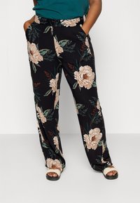 Pantalons noirs à motifs floraux avec de grandes impressions de pivoine beige et des feuilles vertes ; coupe ample avec poches latérales et taille large. Assortis à des sandales neutres.