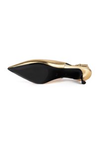 Pump oro in pelle metallica con punta affusolata e sottile tacco nero, superficie liscia e retro arrotondato, caratterizzato da un piccolo dettaglio vicino al tacco.