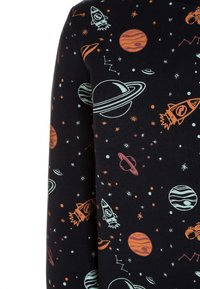 Bavlněná mikina s tmavým pozadím a barevnými grafikami s vesmírnou tematikou, včetně raket, planet a hvězd v různých barvách.