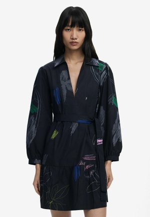 Schwarzes Kleid mit Kragen und langen Ärmeln, das farbenfrohe Blumenmuster aufweist und an der Taille gebunden ist. Leichter Stoff mit fließendem Design.