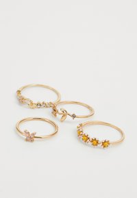 Conjunto de cuatro anillos en tono dorado con piedras preciosas. Los diseños incluyen acentos florales, piedras similares al ópalo y adornos coloridos.