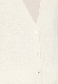 Cardigan beige chiaro fatto di morbido tessuto a maglia, con un profondo scollo a V, cinque bottoni sul davanti e una texture uniforme. I dettagli dei bottoni sono ben evidenti.