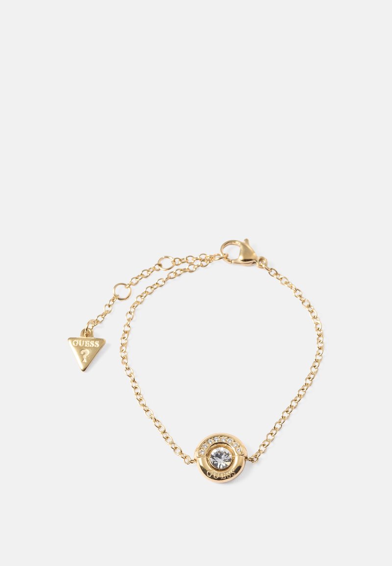 Gullfarget metallarmbånd med en sirkulær anheng som har en klar stein og omgivende rhinesteiner, festet til en kjede med et lite logomerke.