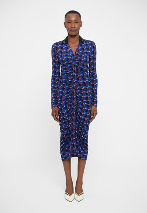 Robe ajustée à manches longues avec un motif géométrique bleu vif et violet. Fabriquée en tissu léger avec des détails froncés et un col.