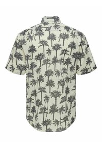 Chemise à manches courtes de couleur crème clair avec un motif de palmier noir. Tissu léger avec un ourlet droit et un col boutonné.