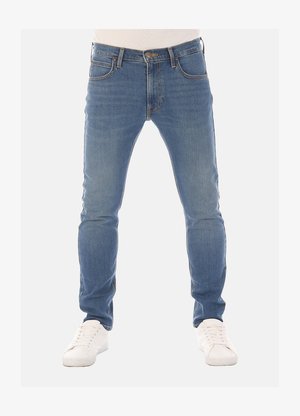 Slim-fit blauwe denim jeans met vijf zakken, riemlussen en subtiele vervaging, gecombineerd met witte sneakers op een neutrale achtergrond.