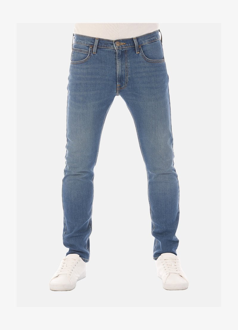 Slim-fit blauwe denim jeans met vijf zakken, riemlussen en subtiele vervaging, gecombineerd met witte sneakers op een neutrale achtergrond.