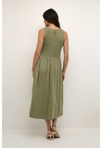 Rochie maxi fără mânici, de culoare verde măslin, cu un corset plisat și un detaliu cu deschidere în spate, având o fustă fluida și o textura moale.
